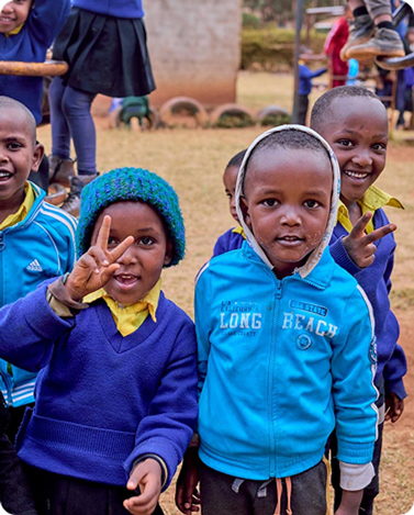 Children at KYCC smiling and gesturing to camera.